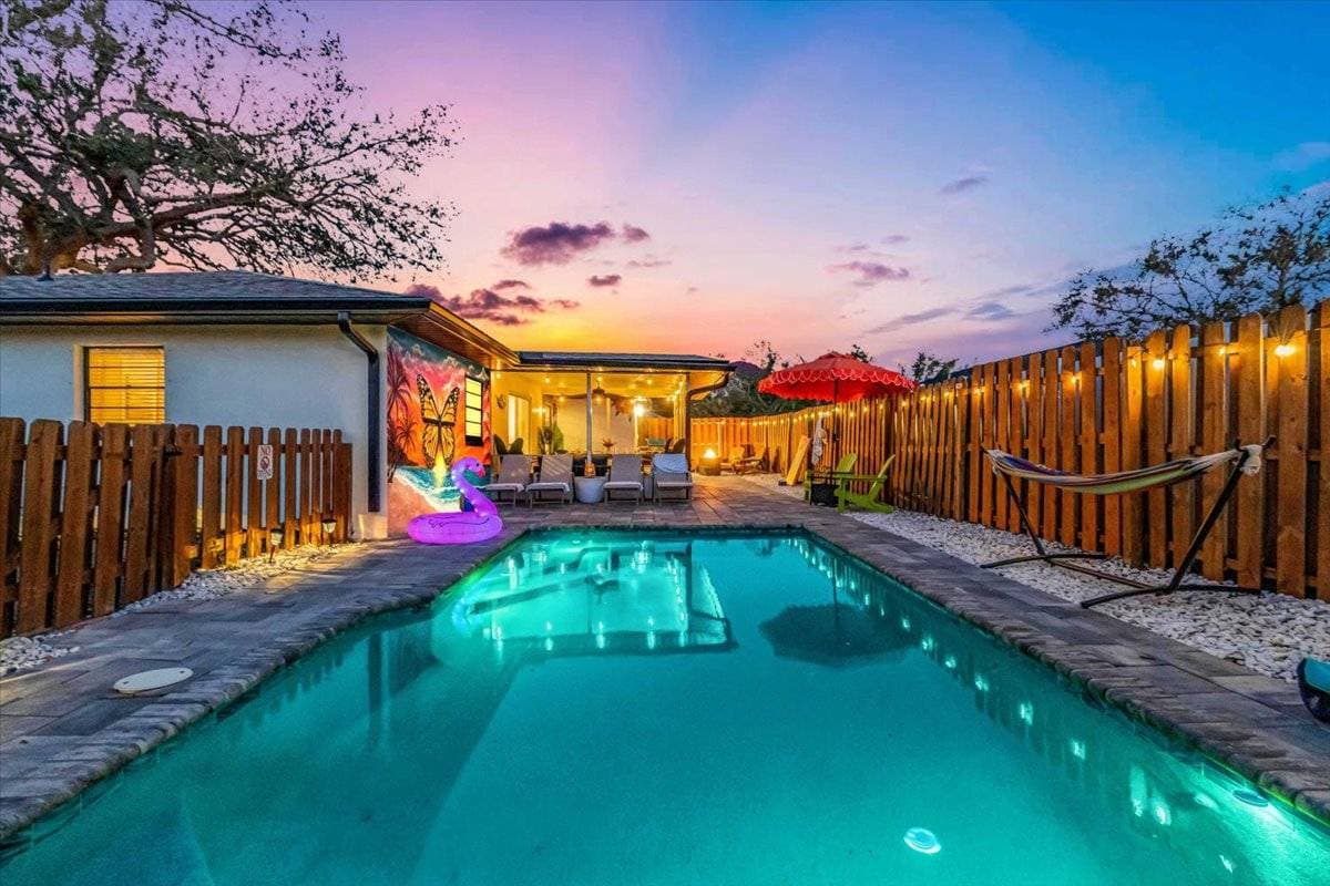 Unwind in your private paradise — this vibrant backyard oasis features a sparkling pool, cozy lounge chairs, a colorful hammock, and enchanting evening lighting. Perfect for unforgettable sunsets and relaxing getaways!